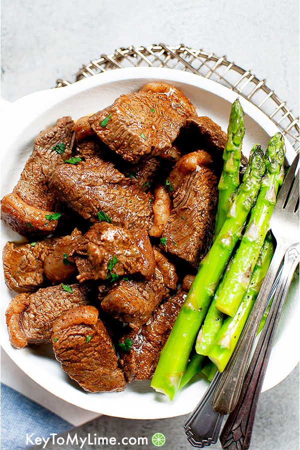 Cajun butter steak bites on a white plate with asparagus.