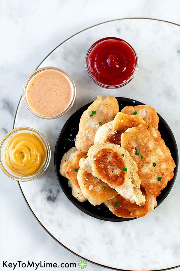 Beer battered chicken tenders with three small containers of dipping sauce.