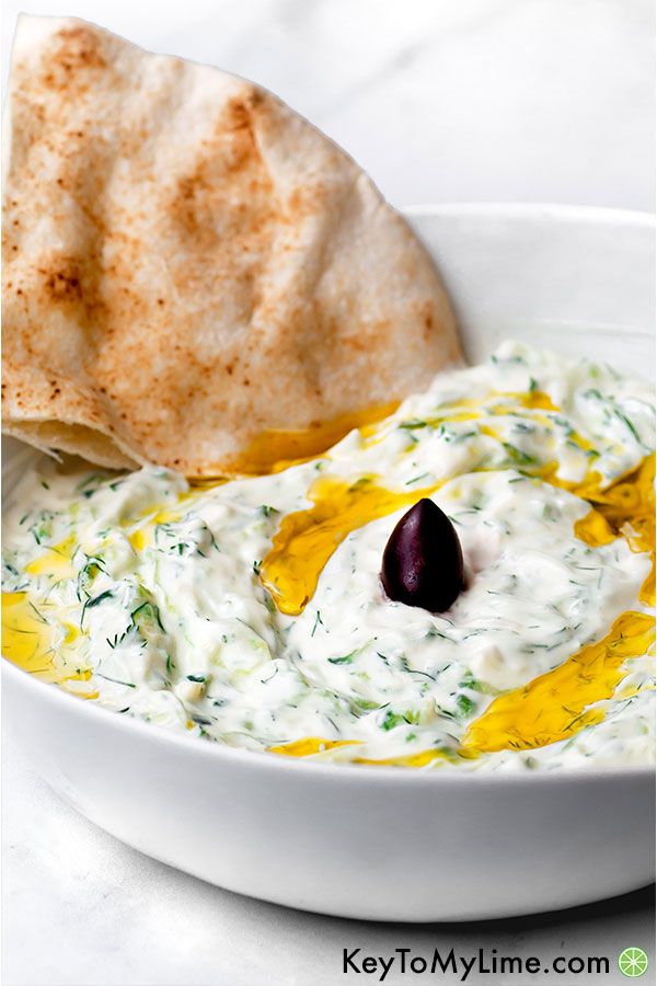Easy tzatziki sauce in a white bowl with a piece of pita.