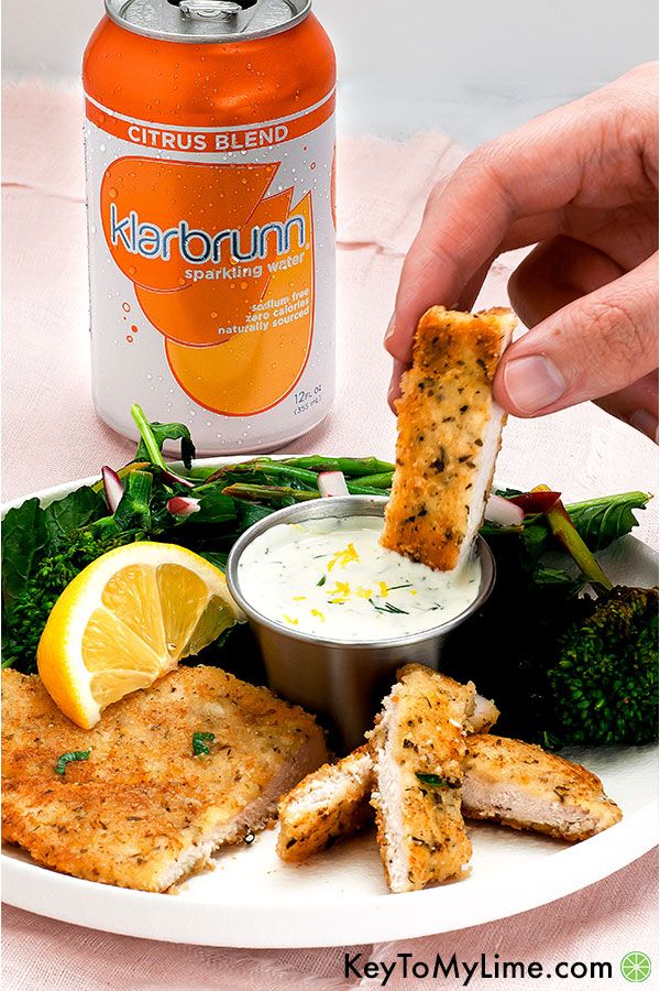 Strips of parmesan crusted chicken being dipped into creamy sauce.