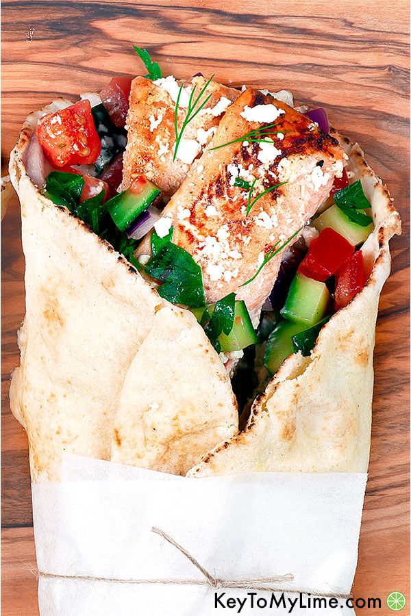 An overhead close up image of a salmon gyro on a wooden board.