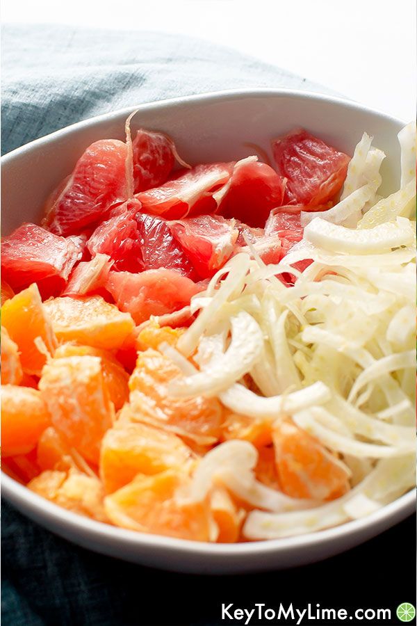 A white bowl with grapefruit, oranges, and slices of fennel.