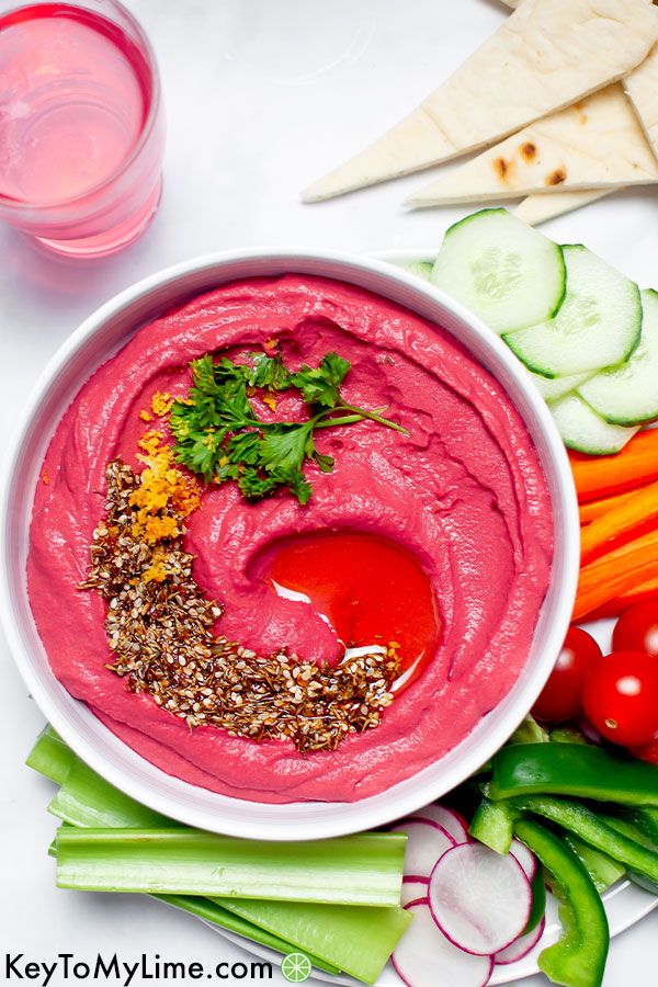 A bowl of vibrant pink beet hummus with parsley on top.