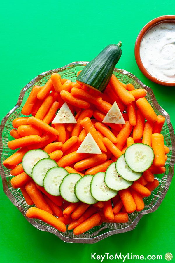 A Jack-o'-Lantern veggie tray made with carrots and cucumber slices.
