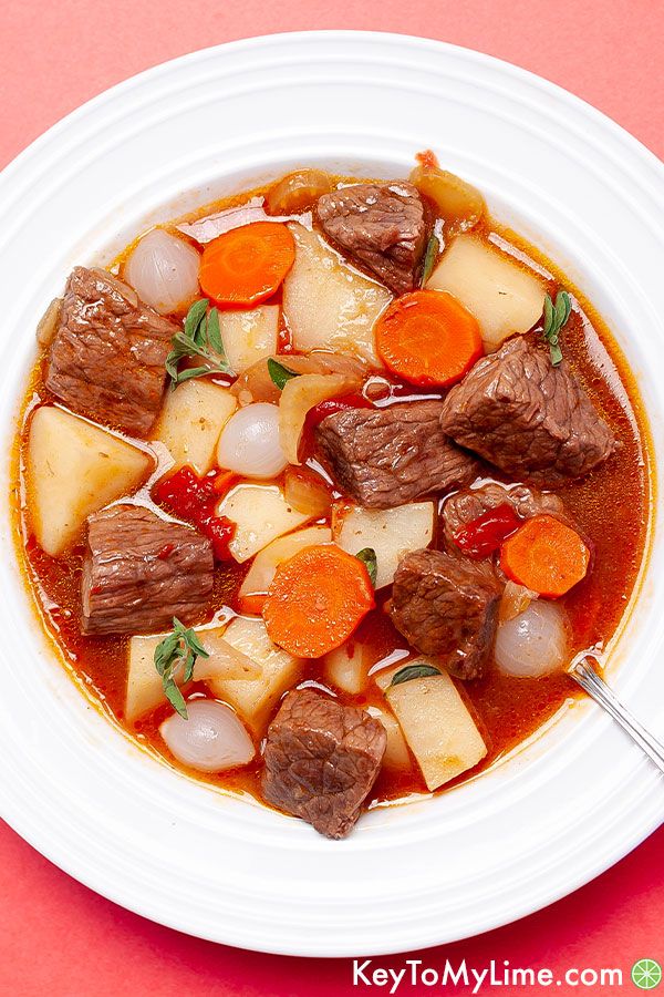 A close up of a bowl of Mulligan stew on a peach background.