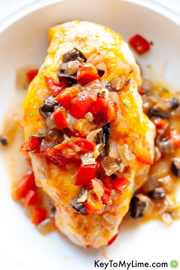 An overhead image of baked chicken breast with diced bell peppers on top.