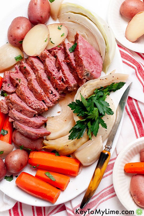 Corned beef with vegetables on a white platter.
