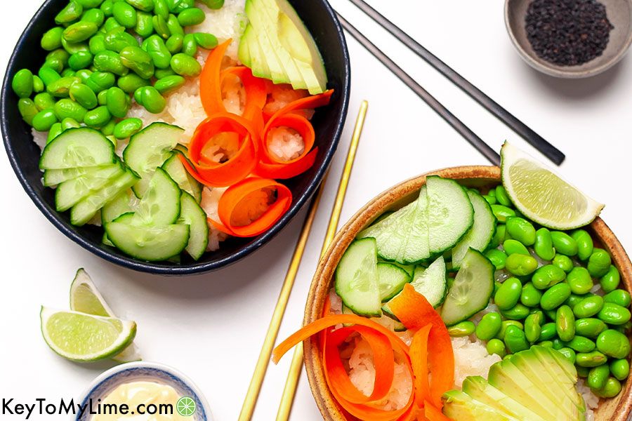 Vegetarian sushi bowls with carrot, avocado, cucumber, and edamame.