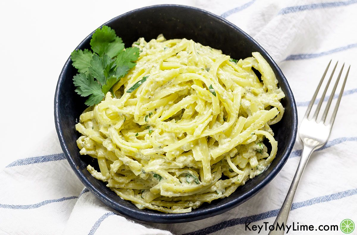 Mexican green spaghetti in a dark bowl on a white background.