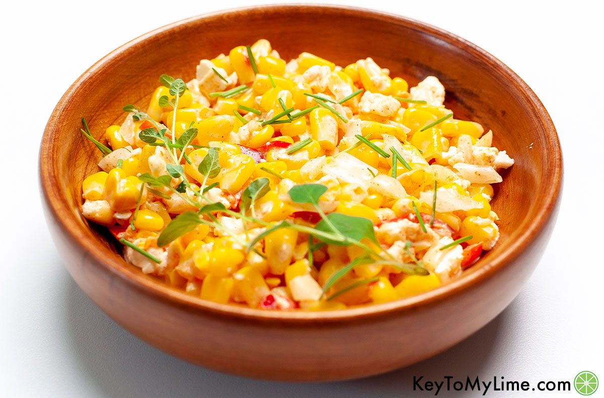 A side image of a wooden bowl filled with Mexican corn salad.