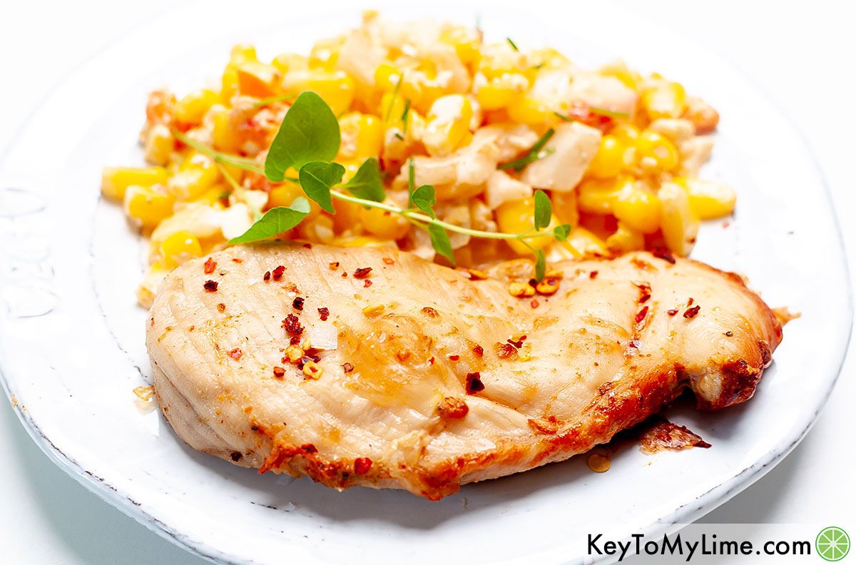 Chili lime chicken on a plate with Mexican street corn salad.