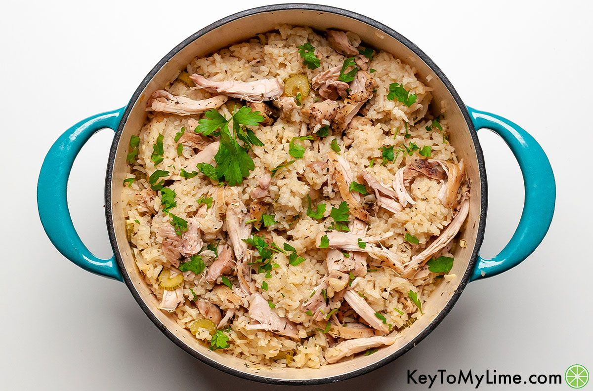 Southern chicken and rice garnished with parsley in a turquoise Dutch oven.