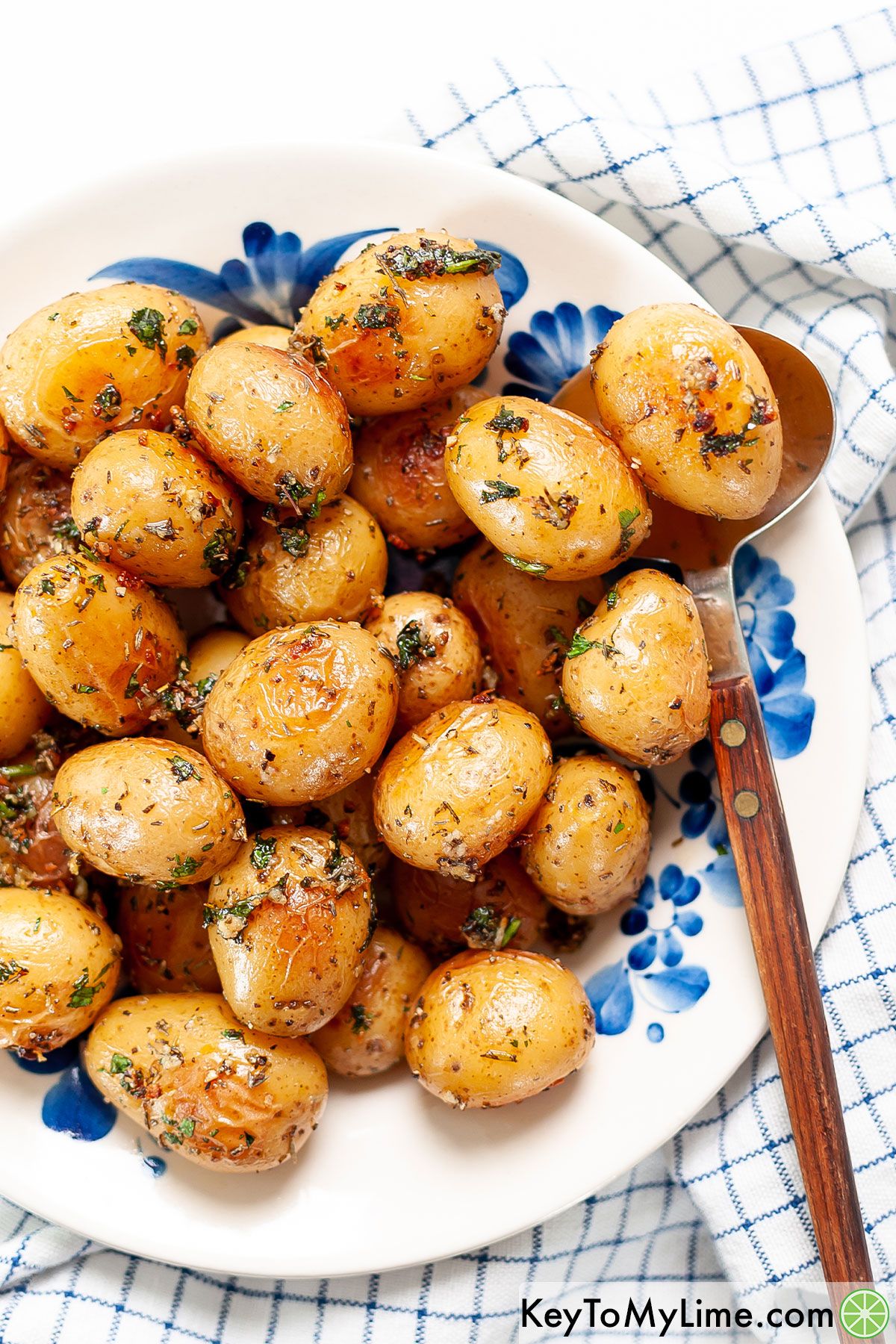 A bowl of roasted baby potatoes with a serving spoon underneath a potato.