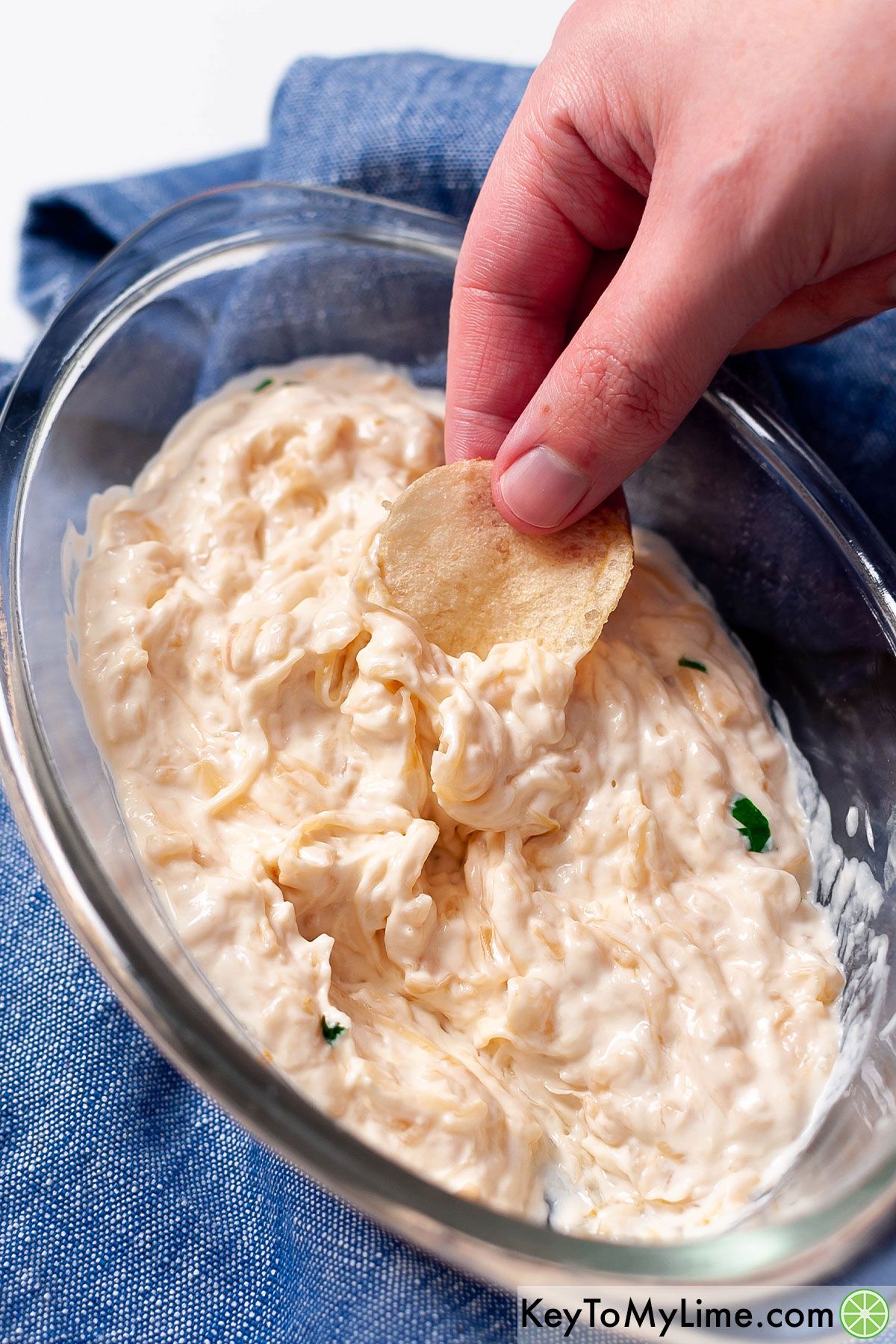 Dipping a potato chip into French onion dip.