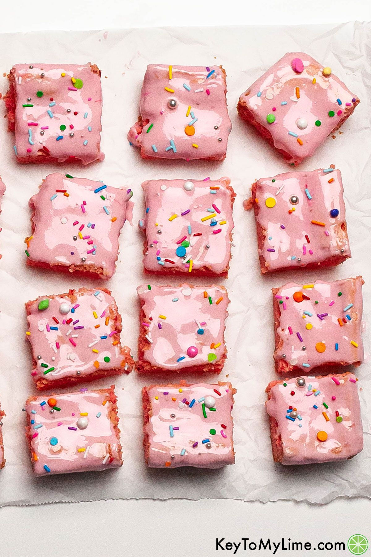 An overhead image of iced strawberry brownies with sprinkles.