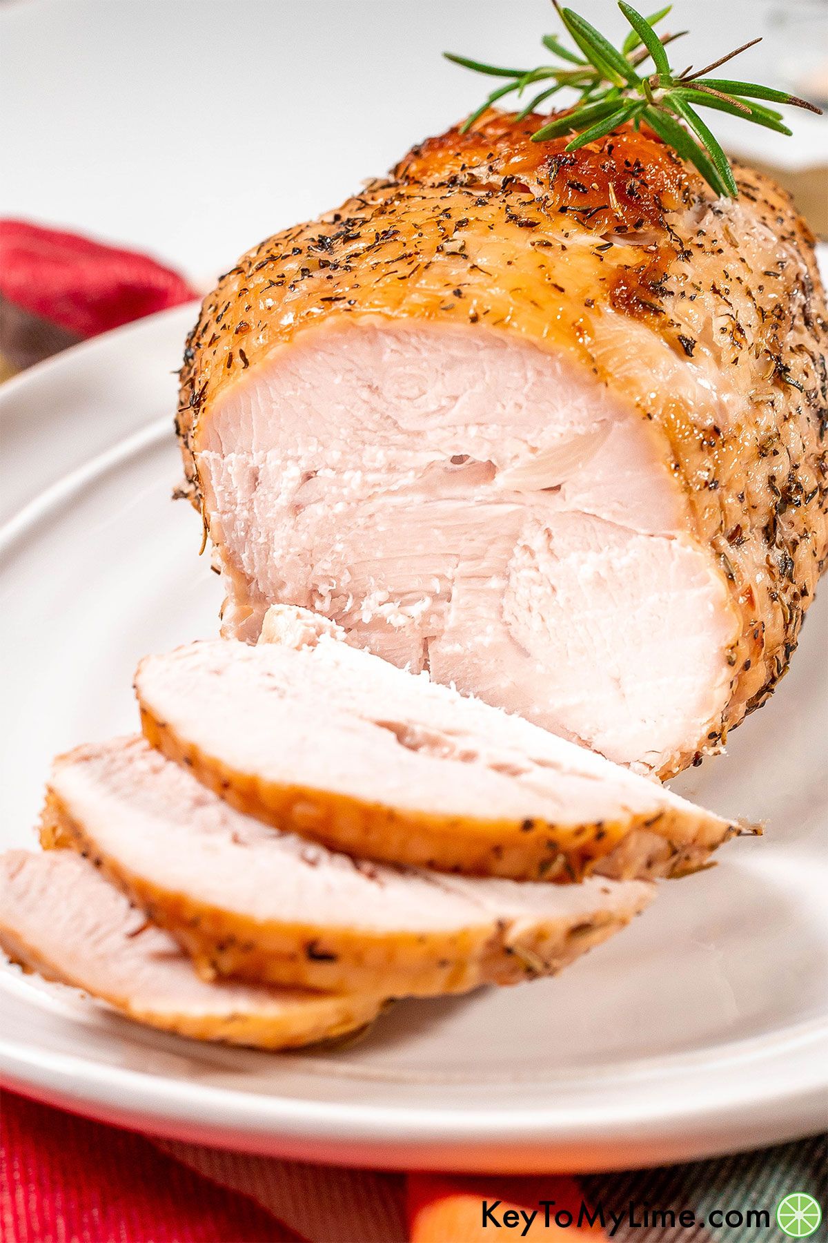 A close up image of multiple slices of turkey breast on a white platter.
