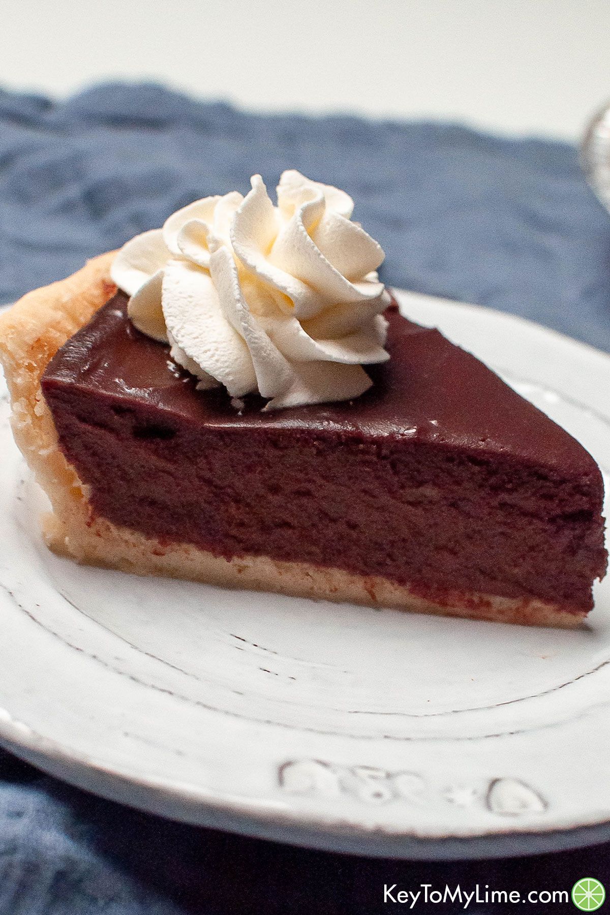 A side image of a slice of chocolate pie with whipped cream on top.