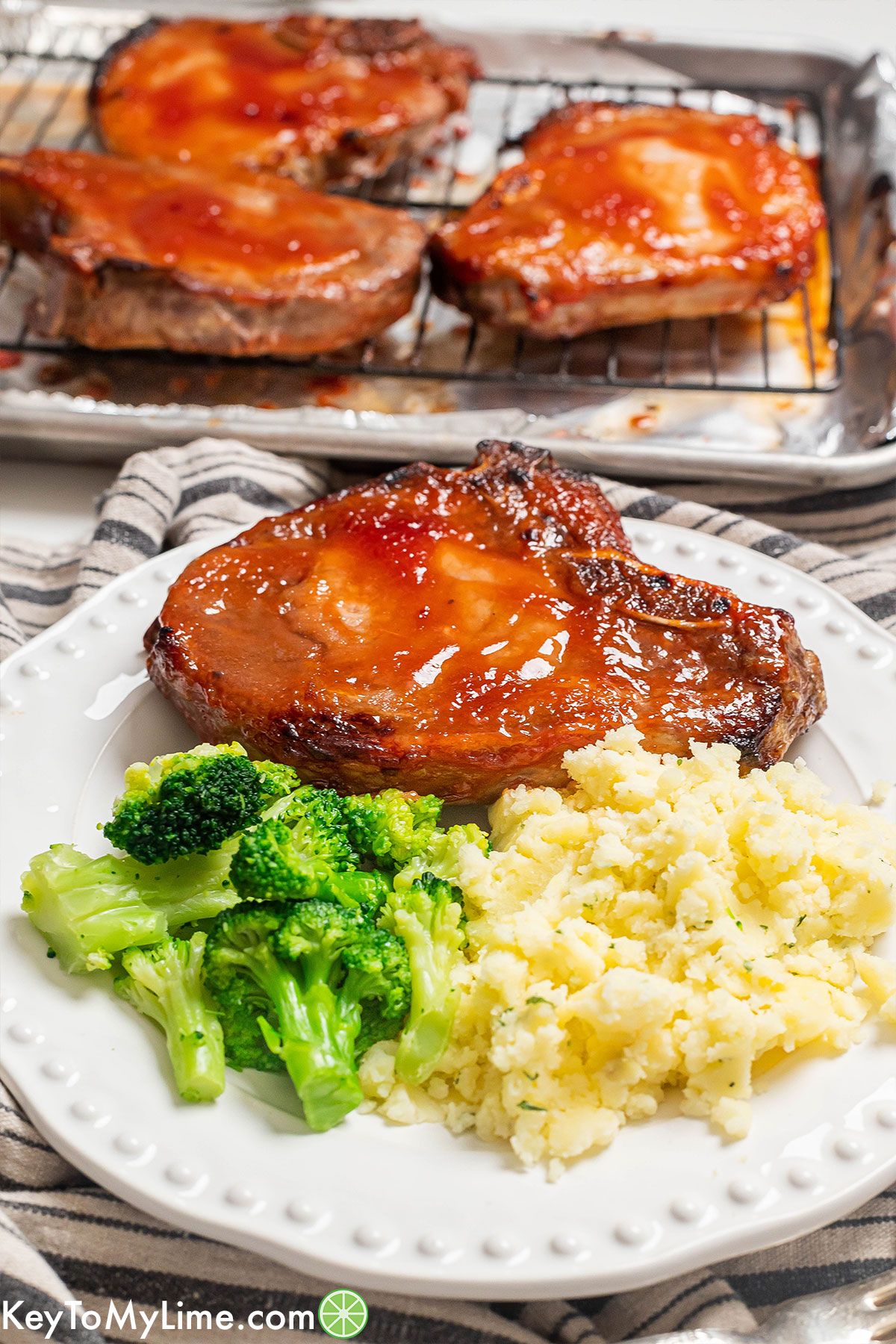 A side shot image showing the texture of the pork chop next to a side of mashed potatoes and broccoli.