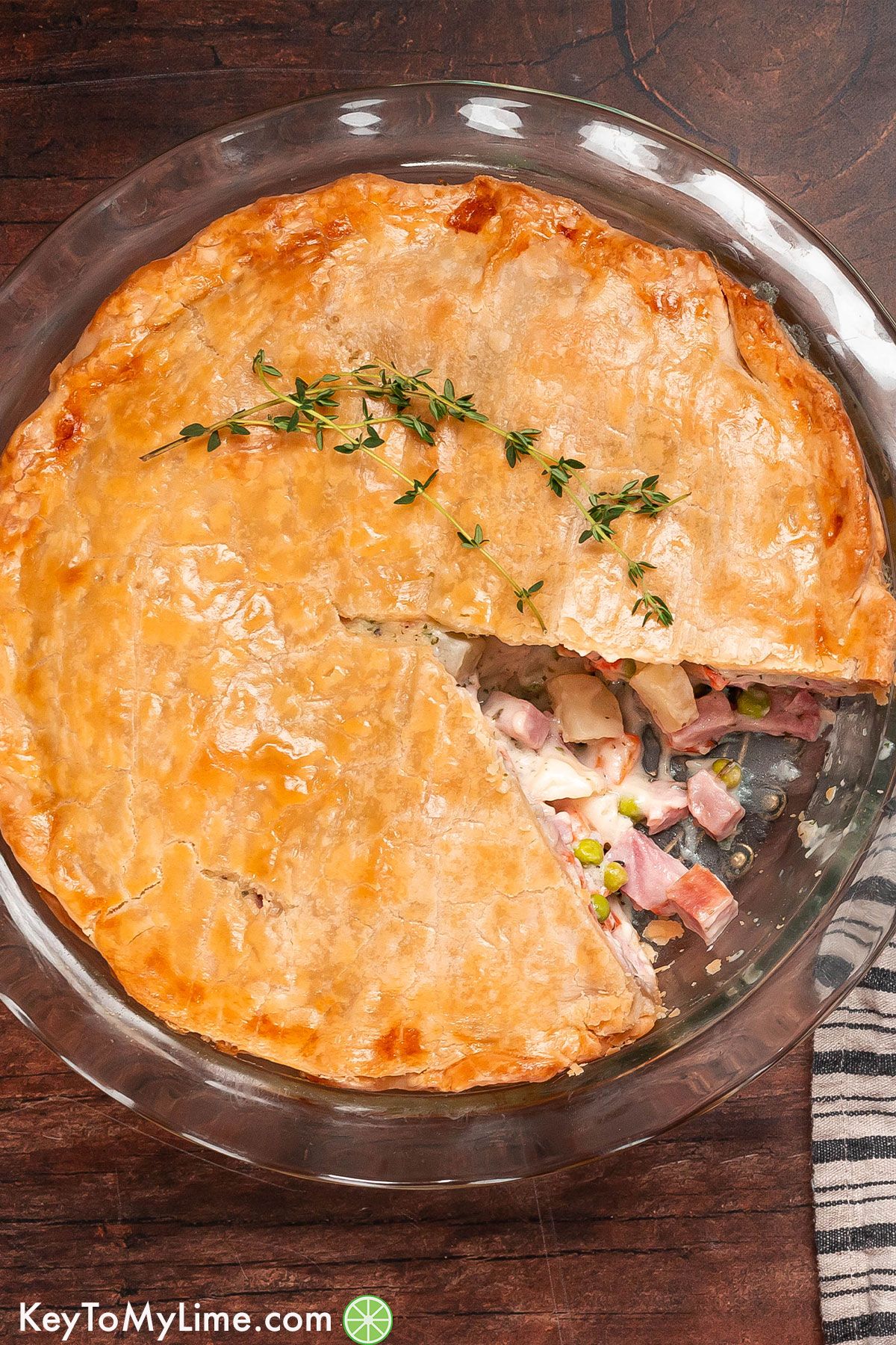 An overhead image of a ham pie with a piece missing in a pie dish.