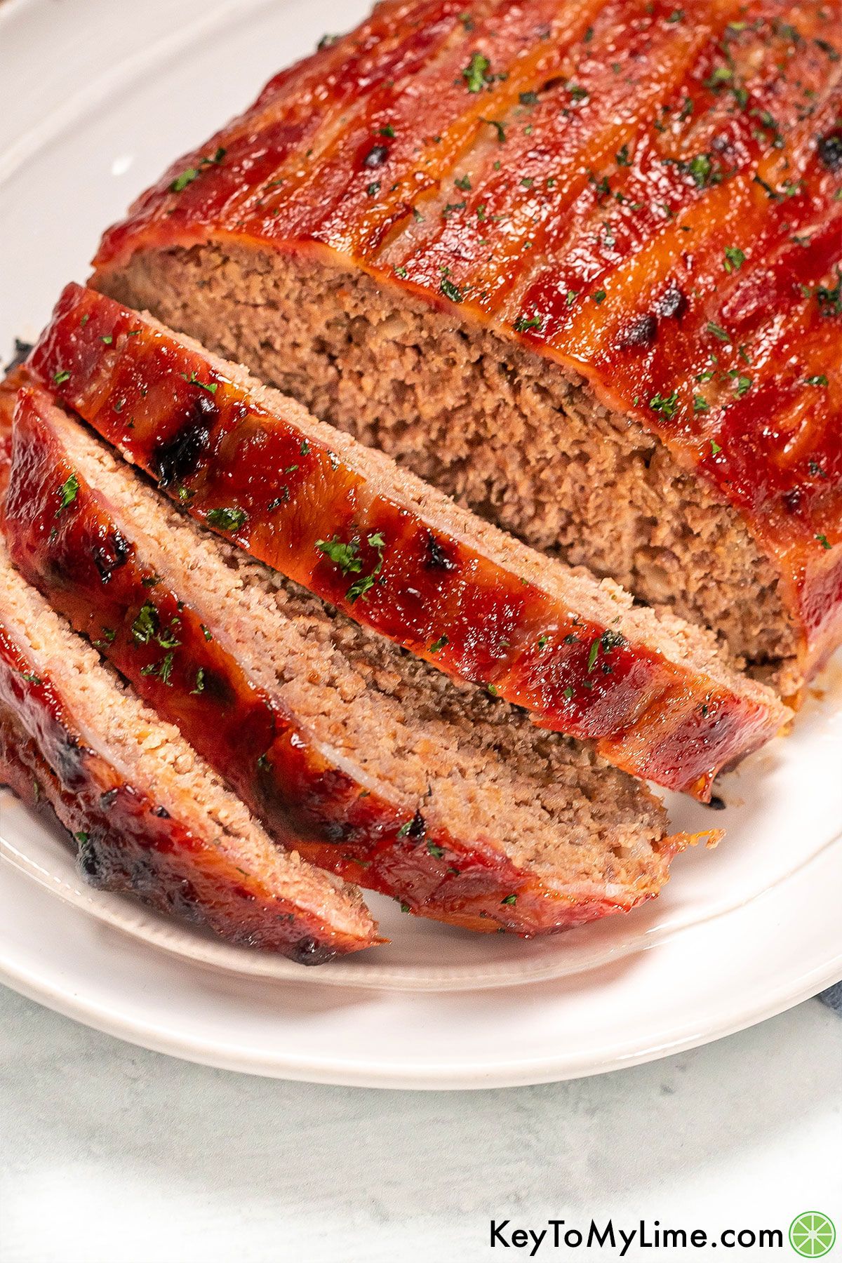 A close-up image showing the glaze of the meatloaf on top of a large white platter.