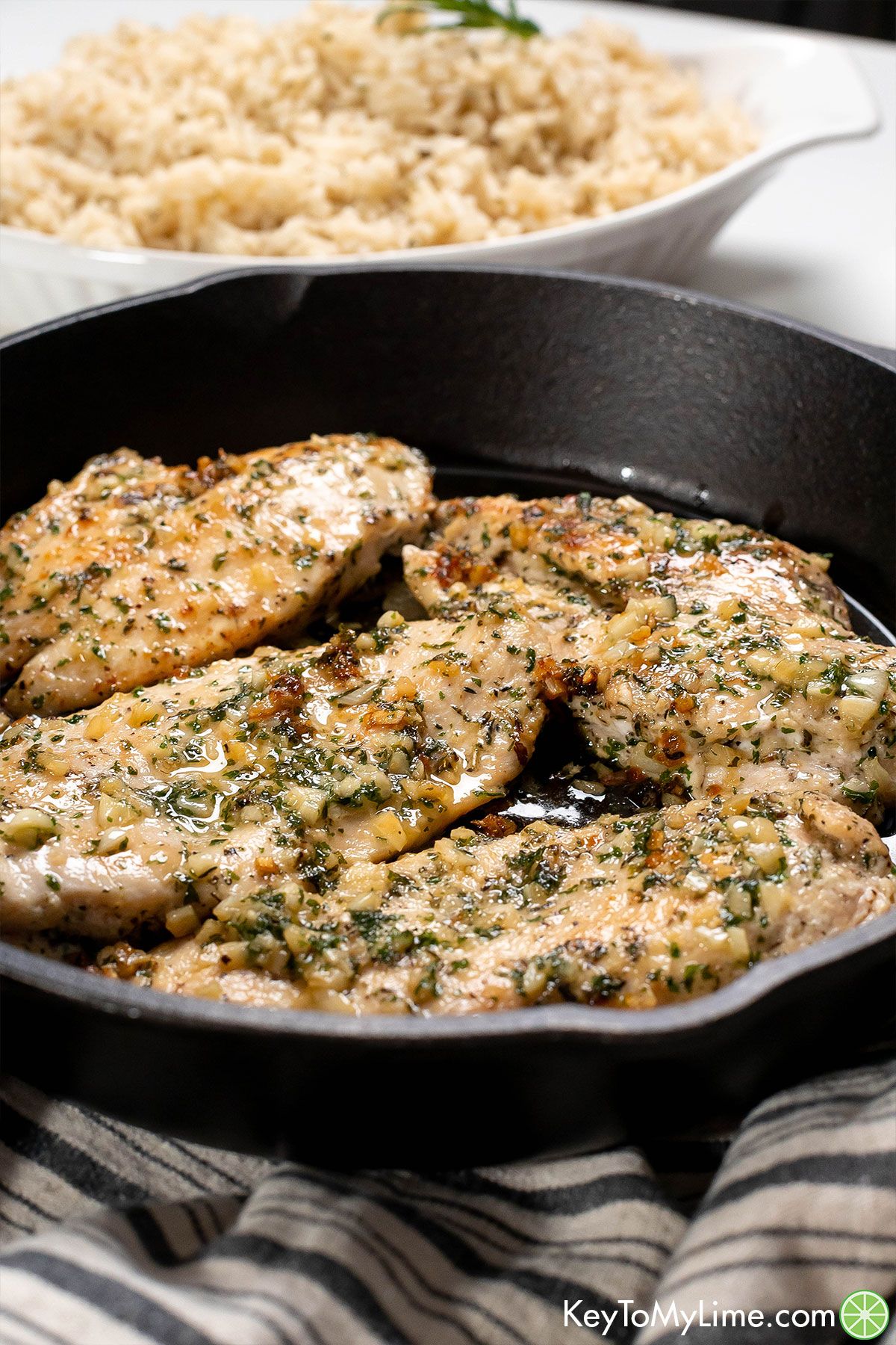 A side shot of seasoned chicken breasts in a cast iron skillet.