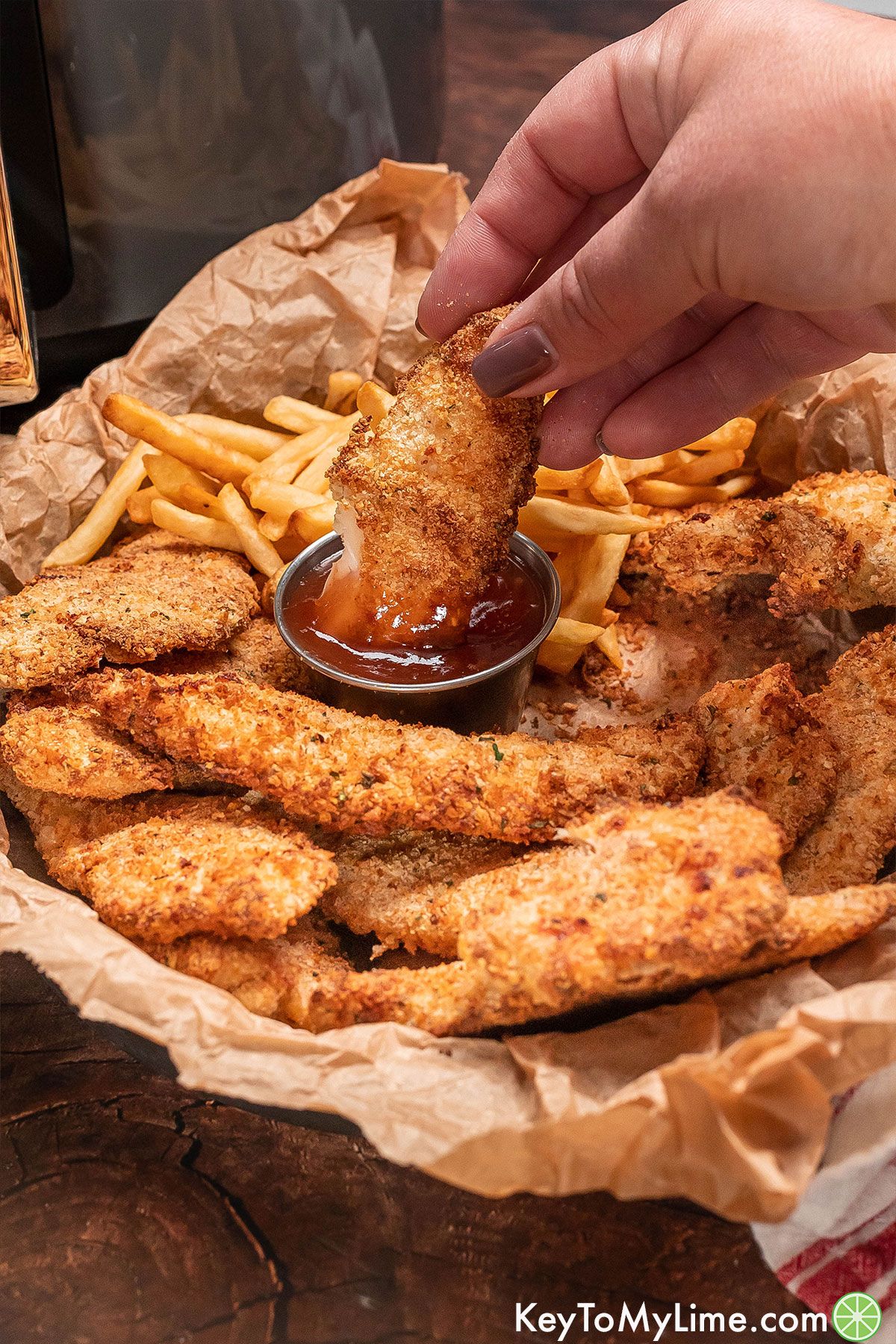 A juicy chicken tender being dipped in sauce.