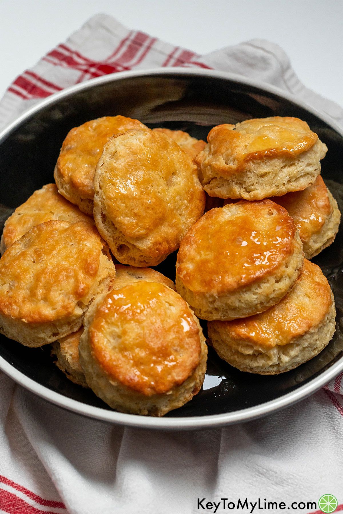 A stack of biscuits inside of a shallow black bowl.