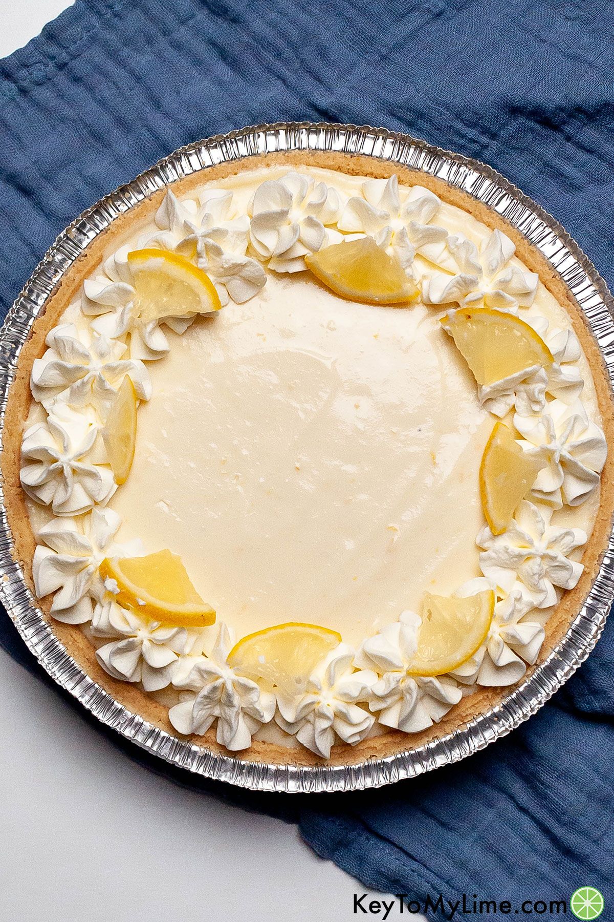 An image of a fully decorated lemon icebox pie in a pie dish on top of a blue napkin.
