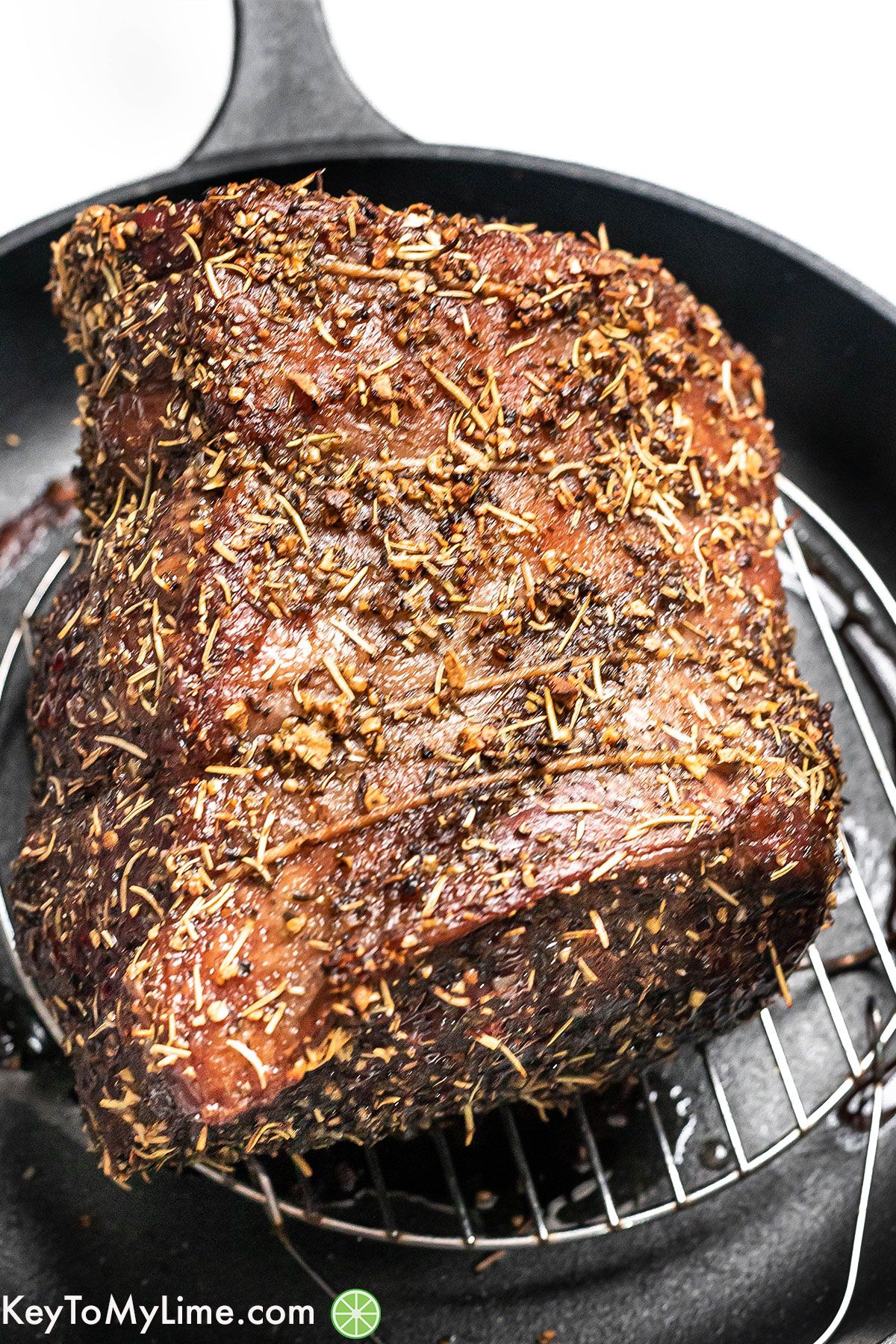 A full roast covered in delicious seasonings in a cast iron skillet after being seared.