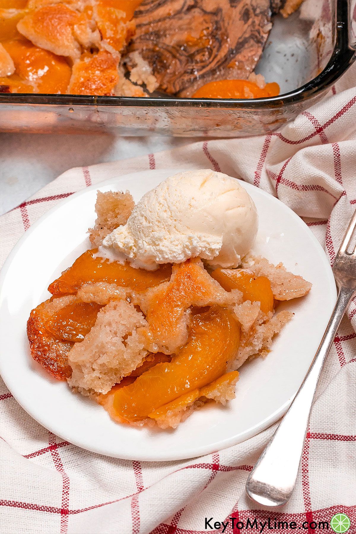 An overhead image of serving of peach cobbler with a scoop of vanilla ice cream on top.