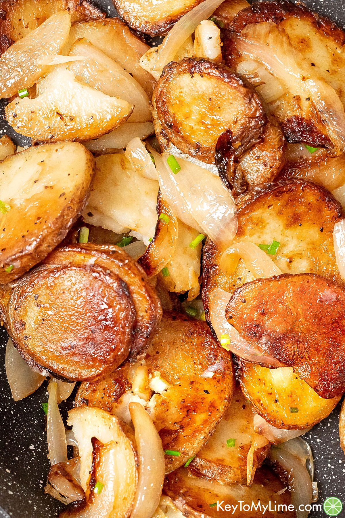 A close up image of freshly garnished potatoes with onions throughout.