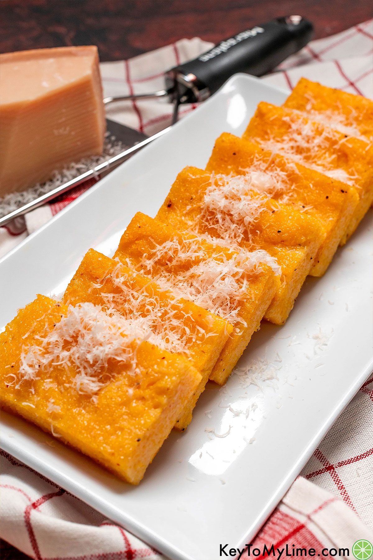 A bunch of garnished and cooked polenta cakes on a serving dish.