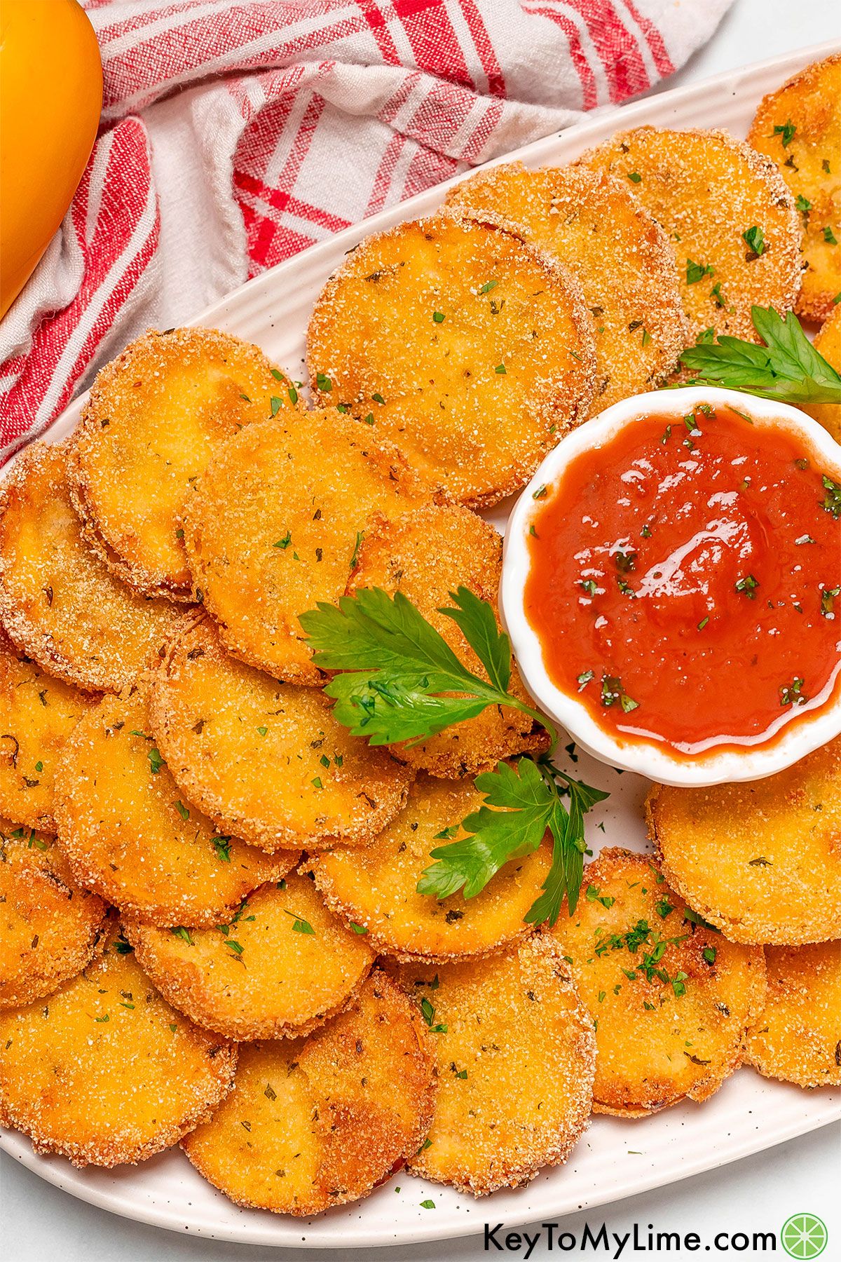 An overhead image of plate full of freshly made fried squash with a side of Marinara sauce.