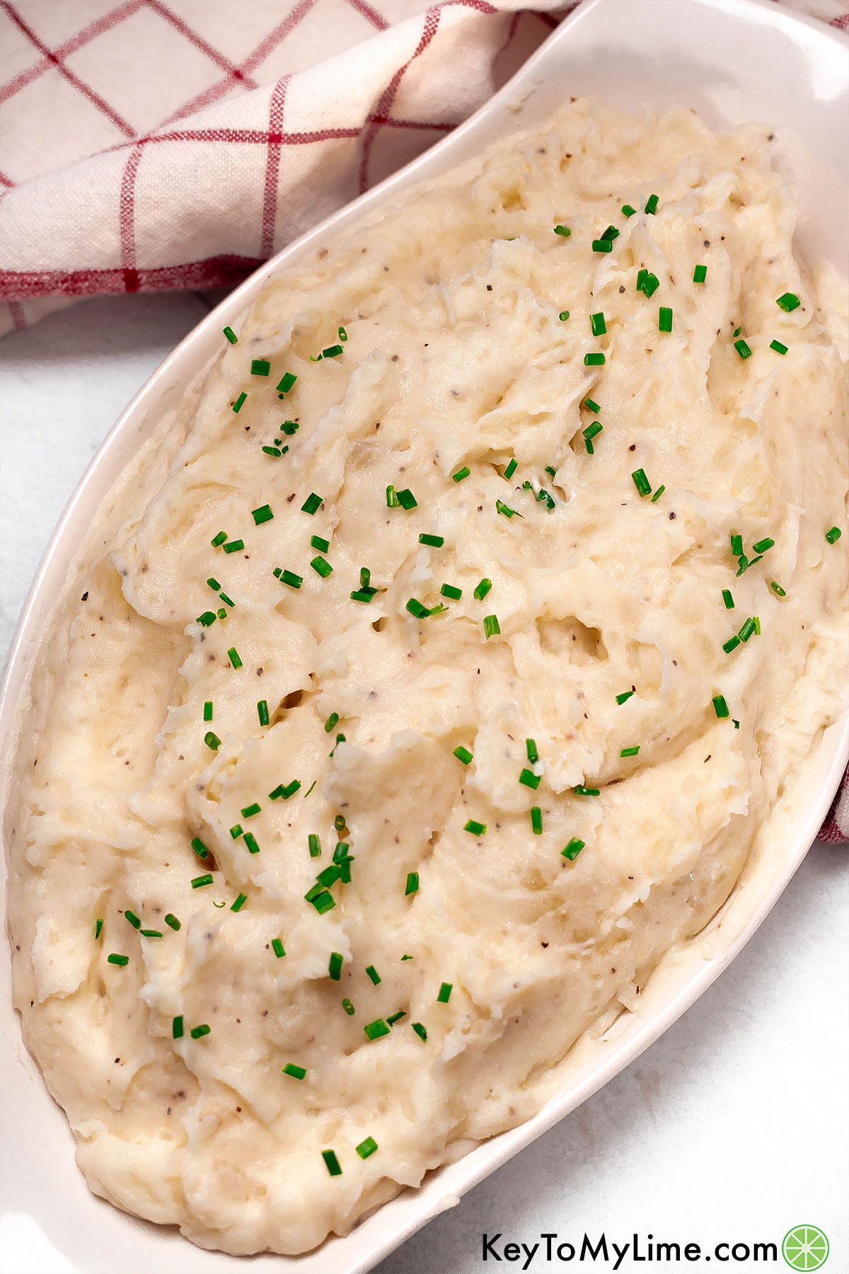 An overhead image of a large serving dish filled with garnished mashed potatoes.