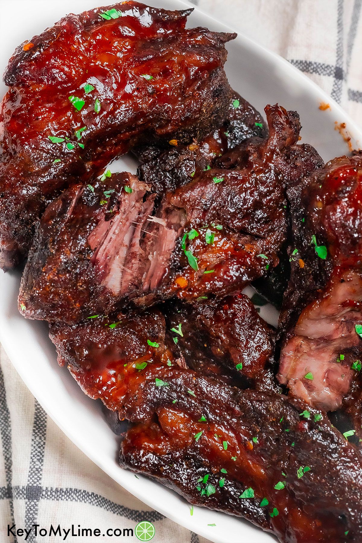 An overhead image of a platter full of garnished ribs.