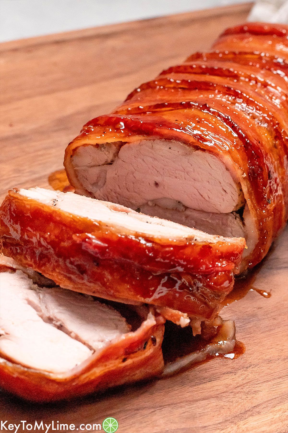 A close up side image showing the inside texture of the pork tenderloin resting on a cutting board.